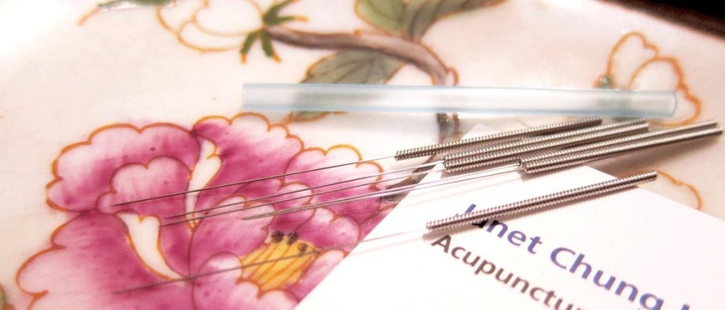 Acupuncture needles resting on a hand-painted Chinese porcelain plate